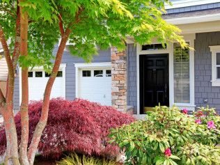 House exterior with red Japanese maple, garage, and black front door.