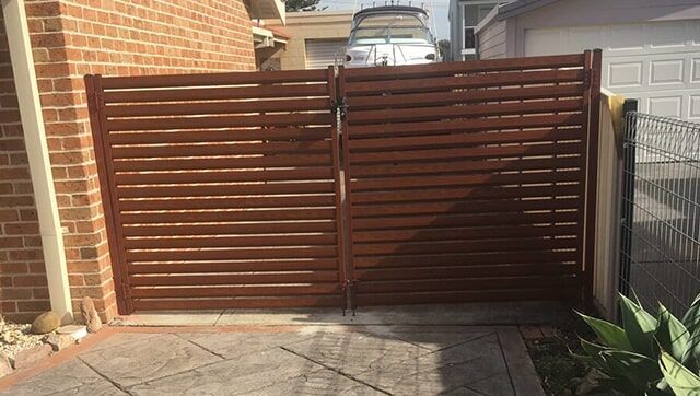 A White Fence is Sitting next to a White wall — Fencing in Port Stephens, NSW