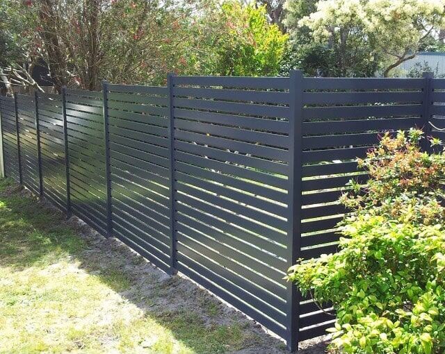 A Black Fence is Surrounded by Grass and Trees in a Yard — Fencing in Port Stephens, NSW