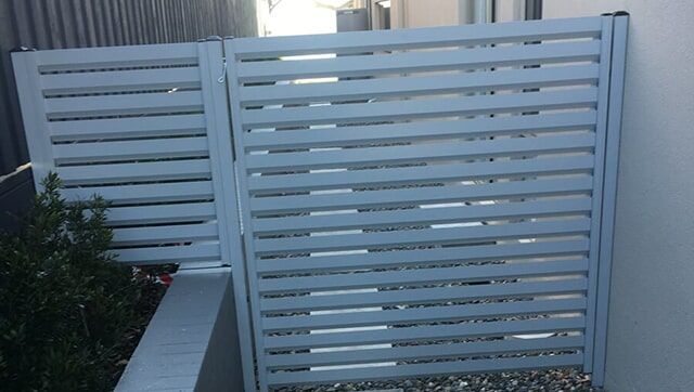 A White Fence is Sitting next to a White wall — Fencing in Port Stephens, NSW