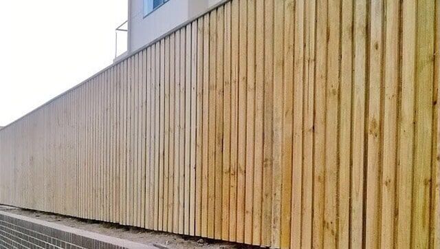 A Wooden Fence is Sitting next to a Building — Fencing in Port Stephens, NSW