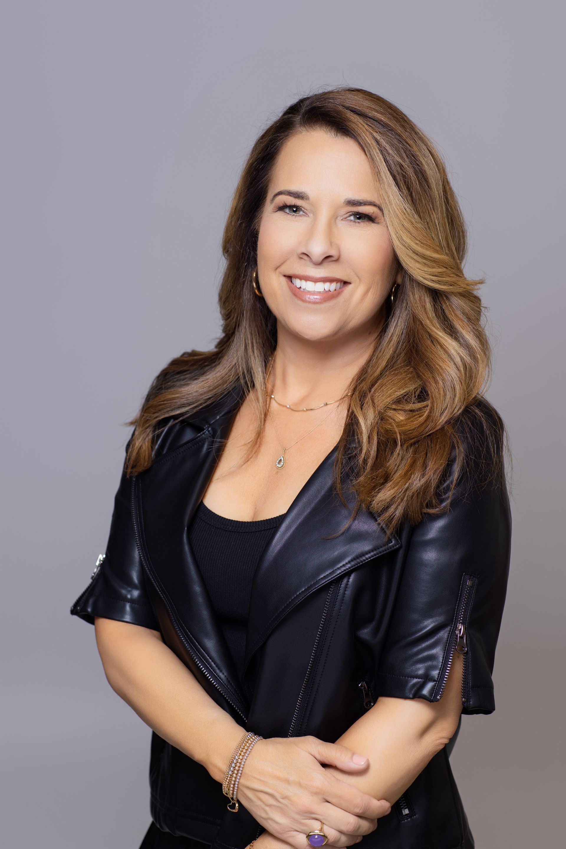 A woman in a black leather jacket is smiling for the camera.