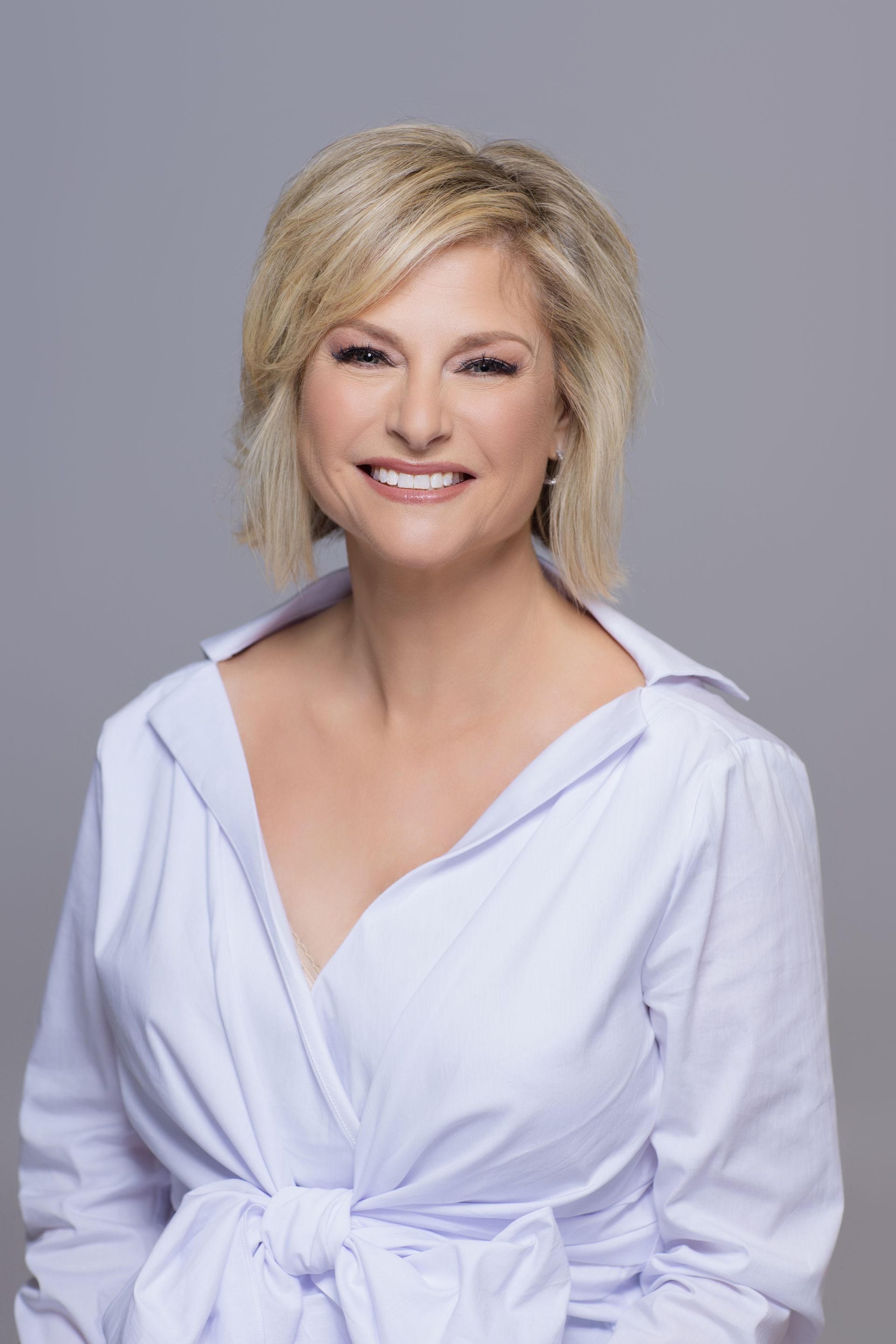 A woman in a white shirt is smiling for the camera.