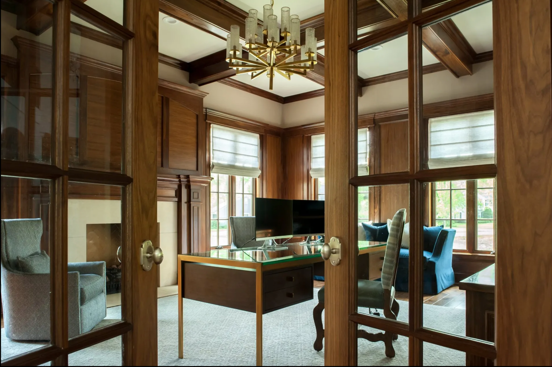 A living room with a desk and chairs and a chandelier