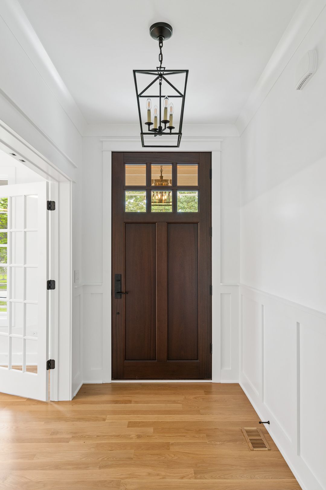 A hallway with a wooden door and a lantern hanging from the ceiling