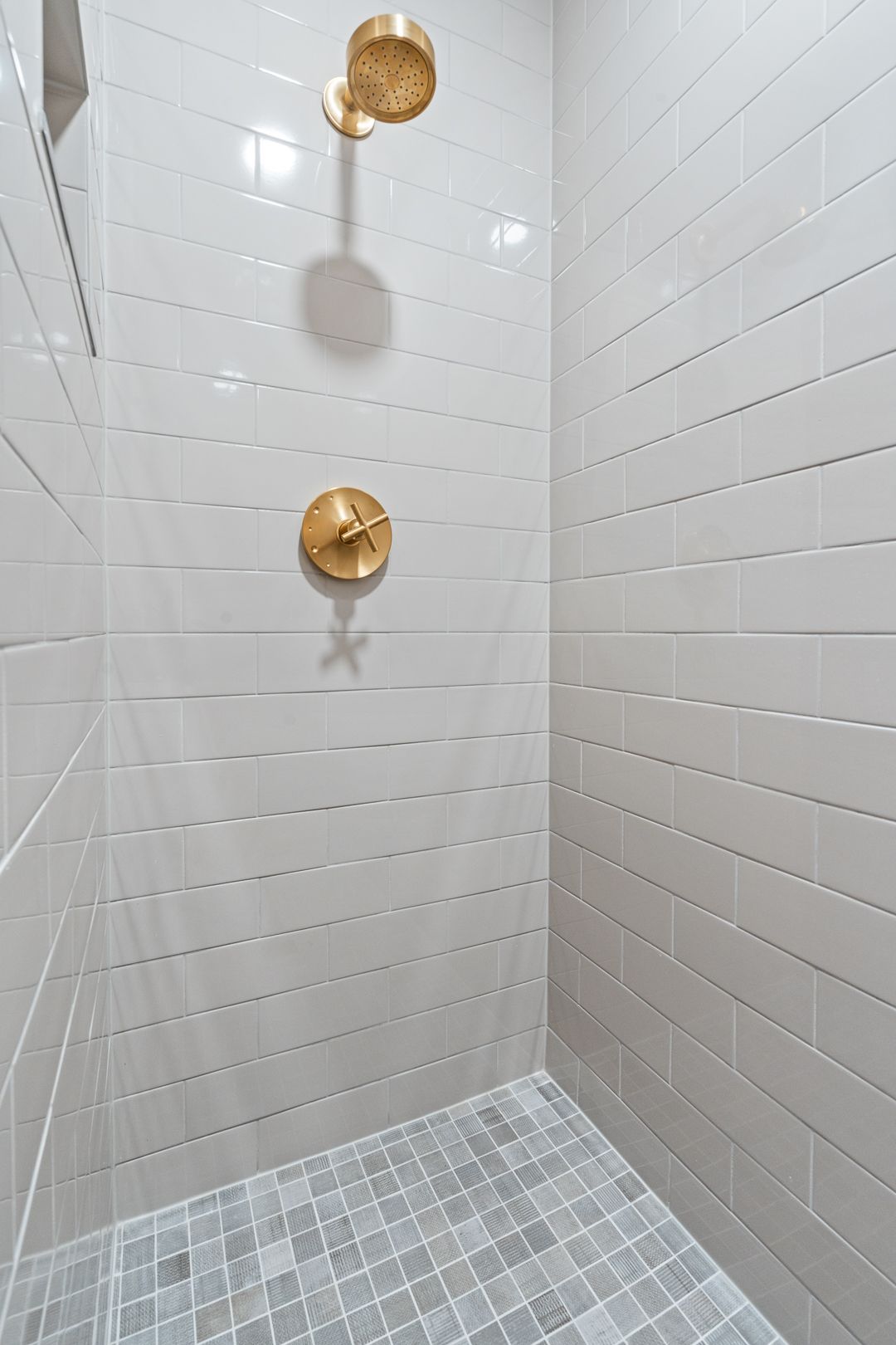 A shower with two shower heads and a tiled floor.