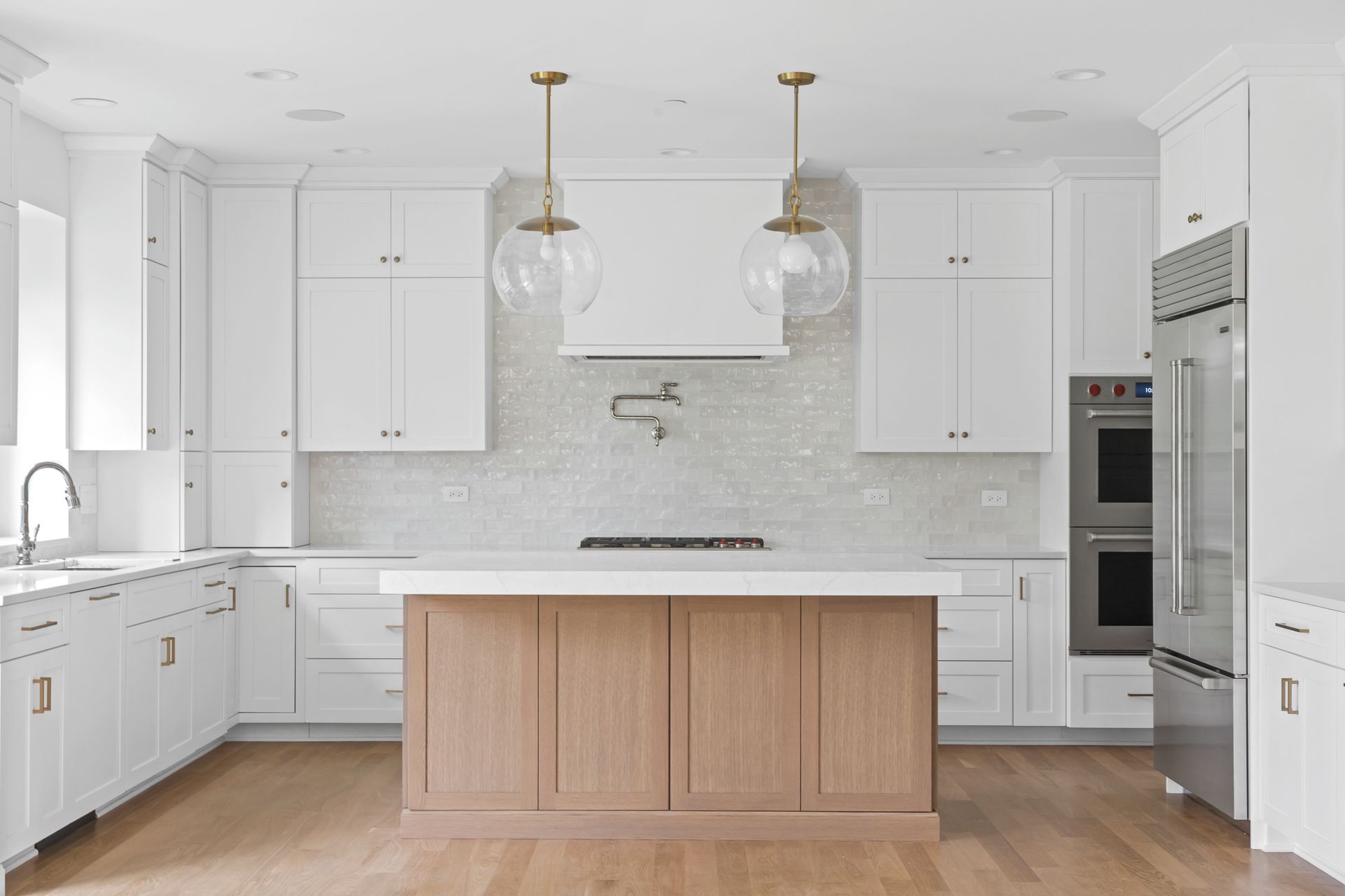 A kitchen with white cabinets and a wooden island