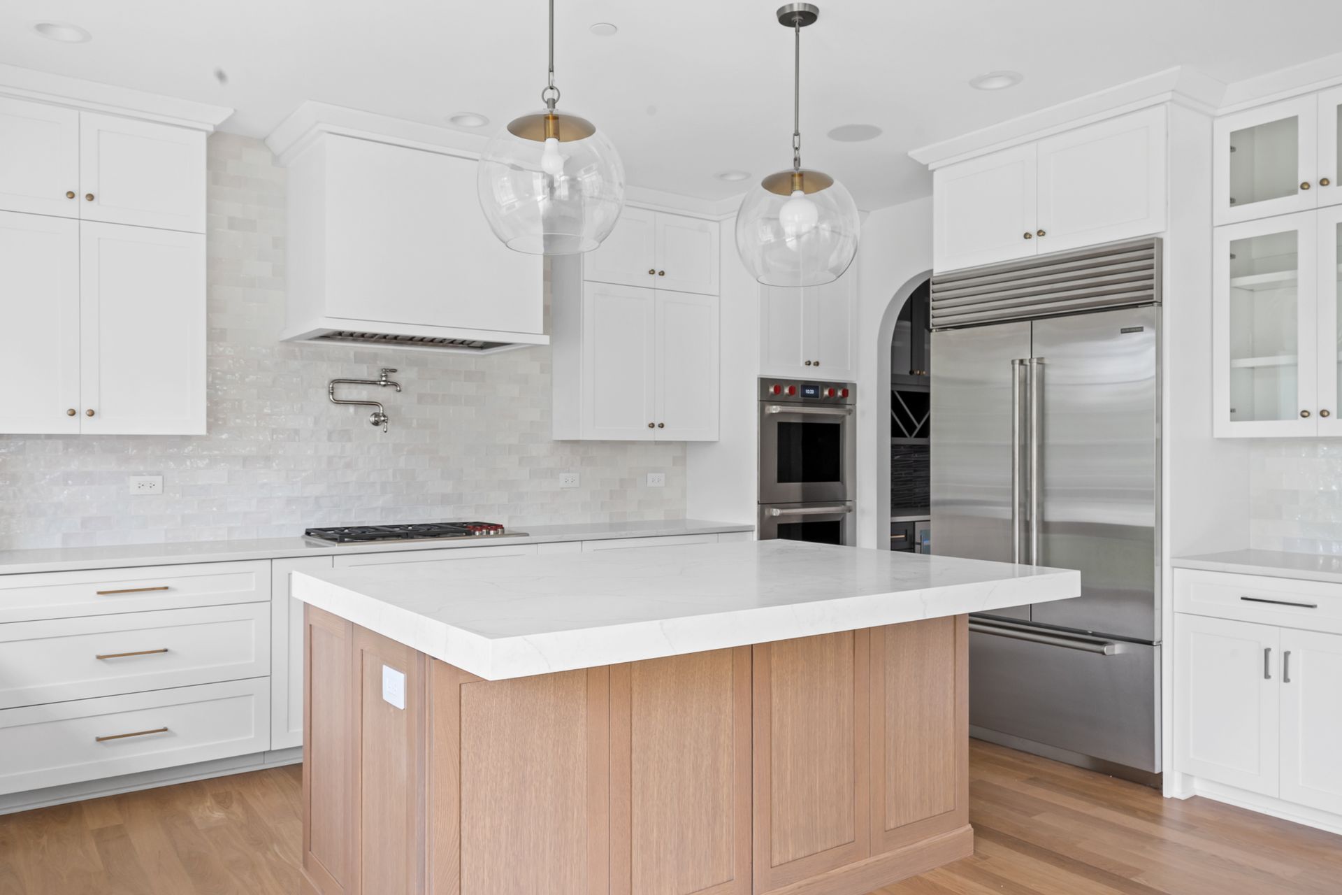 A kitchen with white cabinets , stainless steel appliances , and a large wooden island.