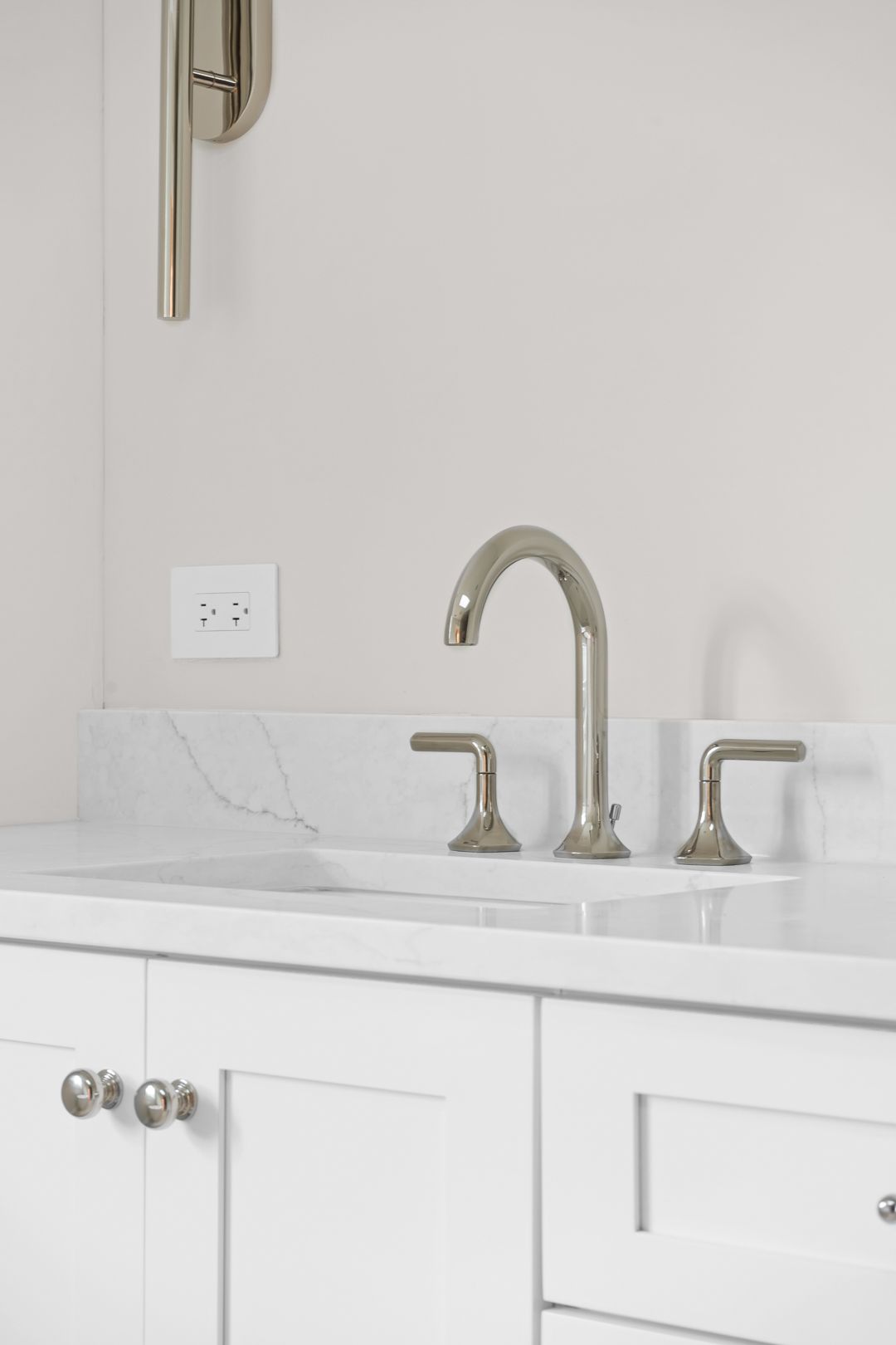 A bathroom sink with white cabinets and a faucet.