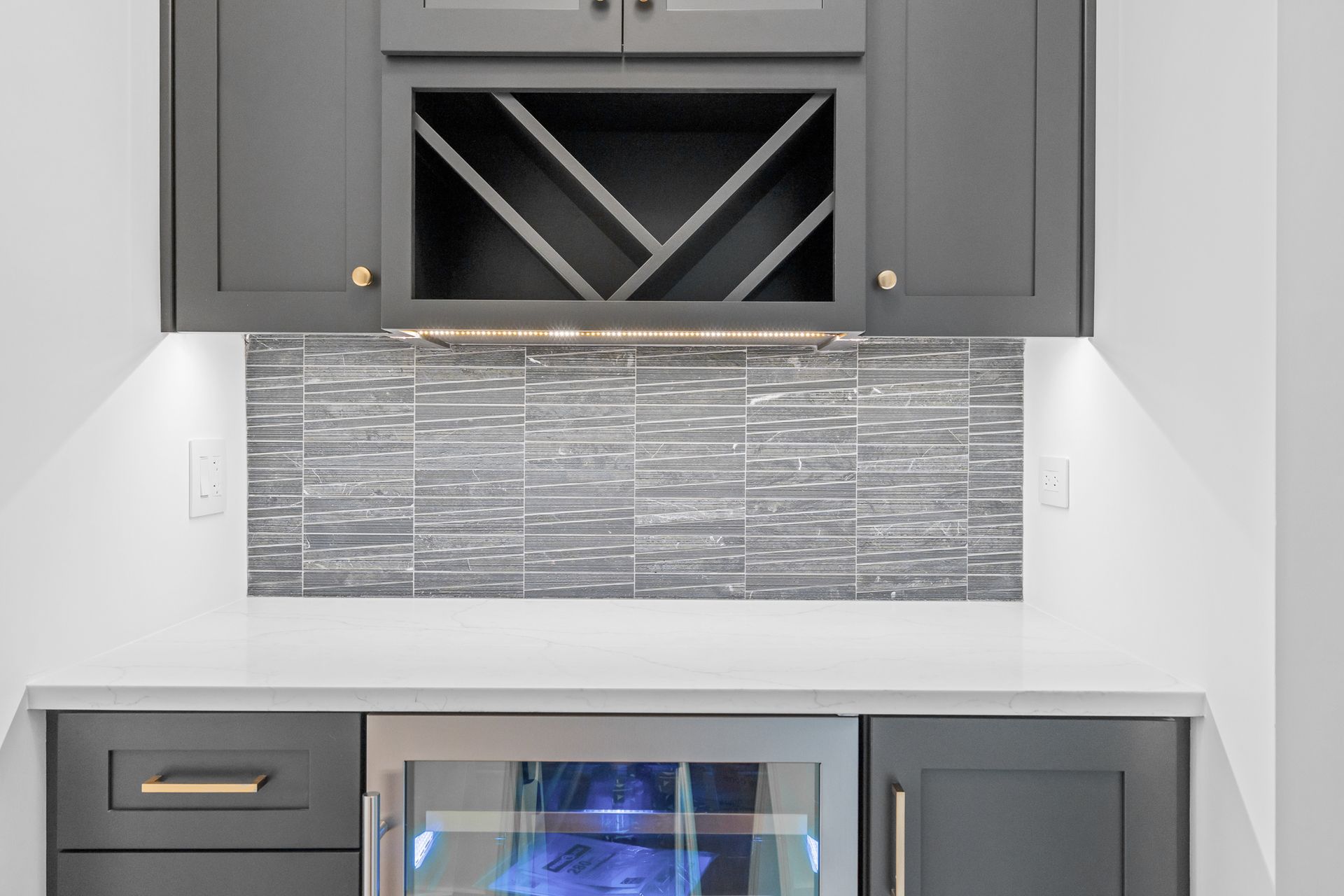 A kitchen with gray cabinets , a wine rack and a refrigerator.