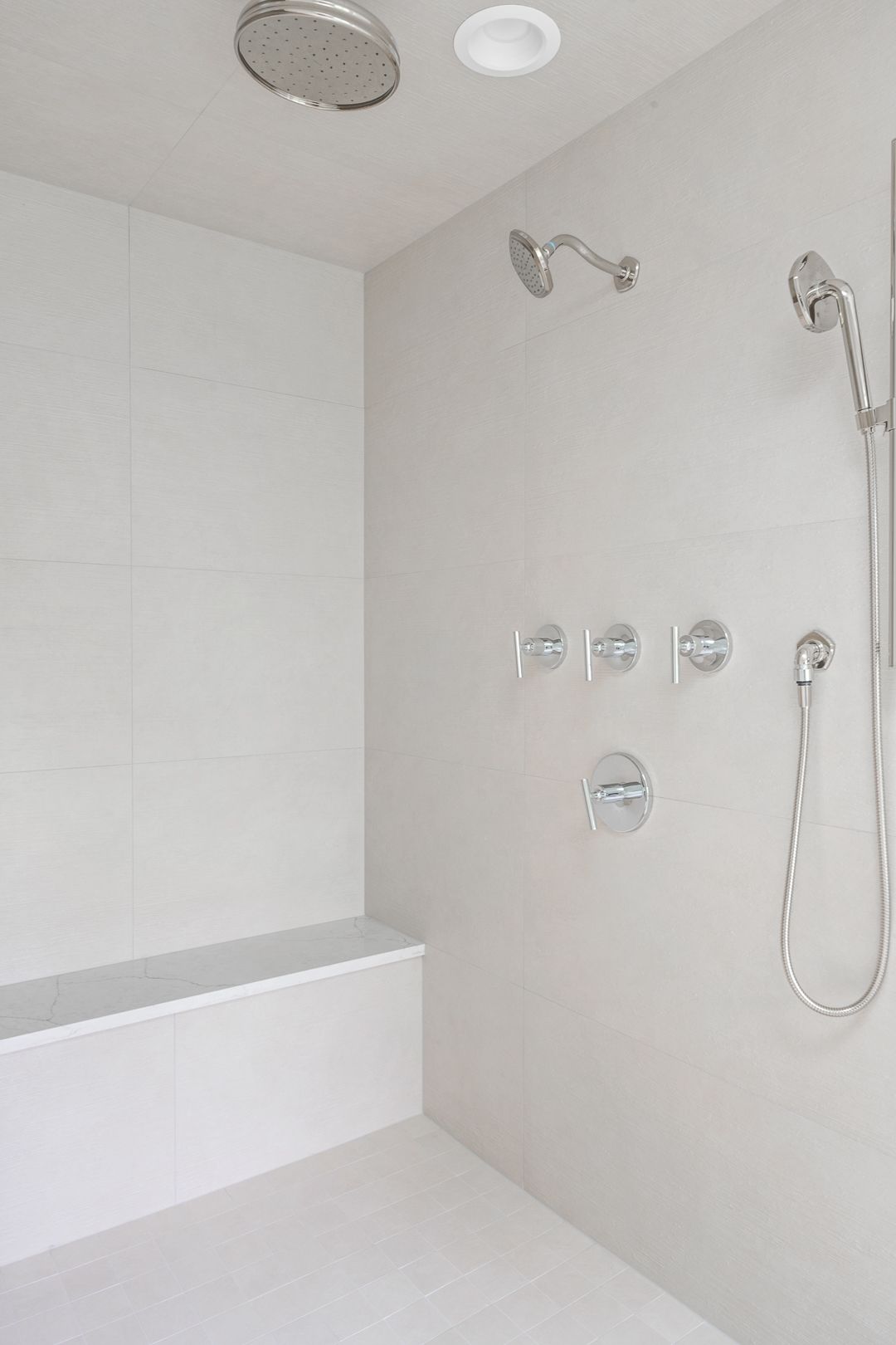 There is a shower with a bench and a shower head.