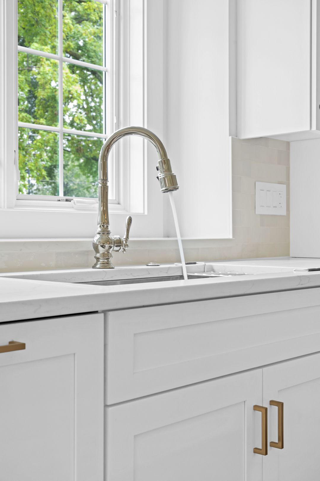 A kitchen sink with a faucet and a window in the background.