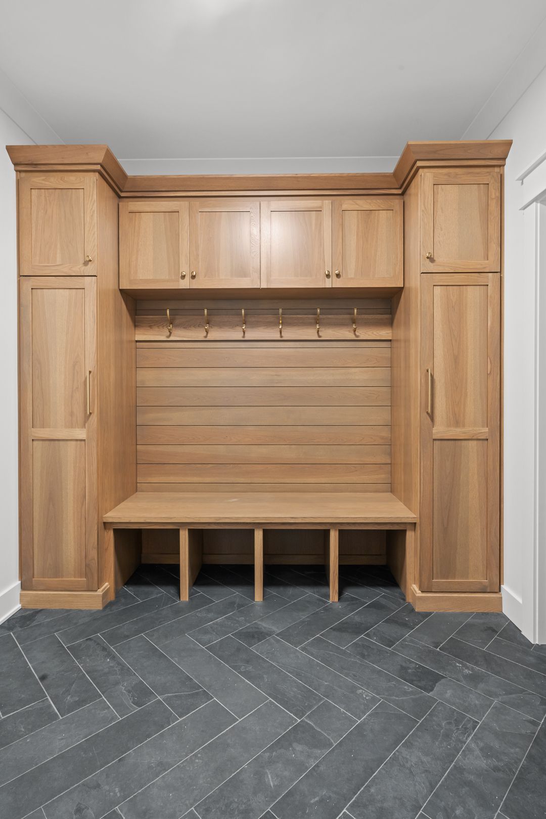 A mud room with wooden cabinets and a bench.