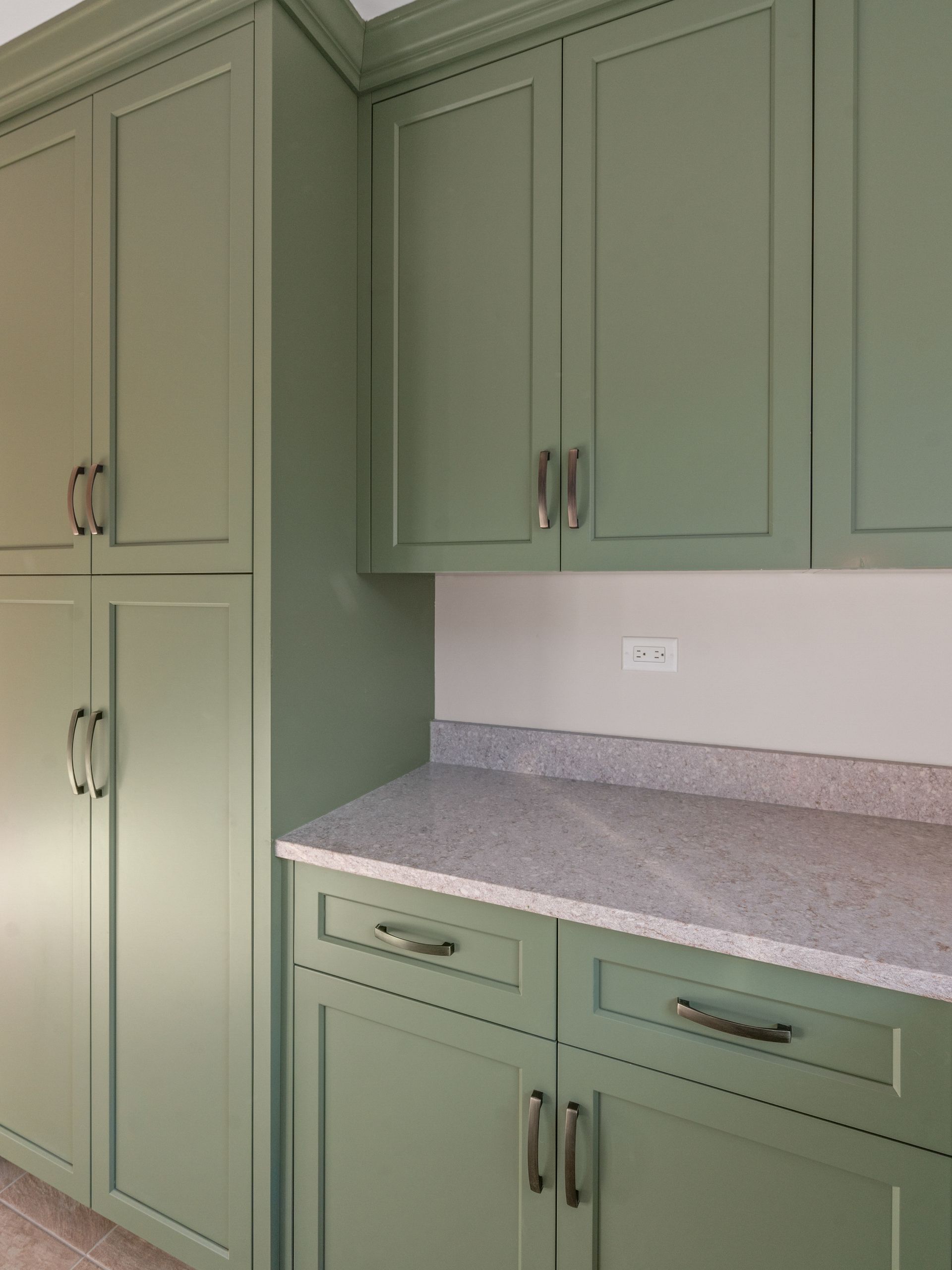 A kitchen with green cabinets and a granite counter top
