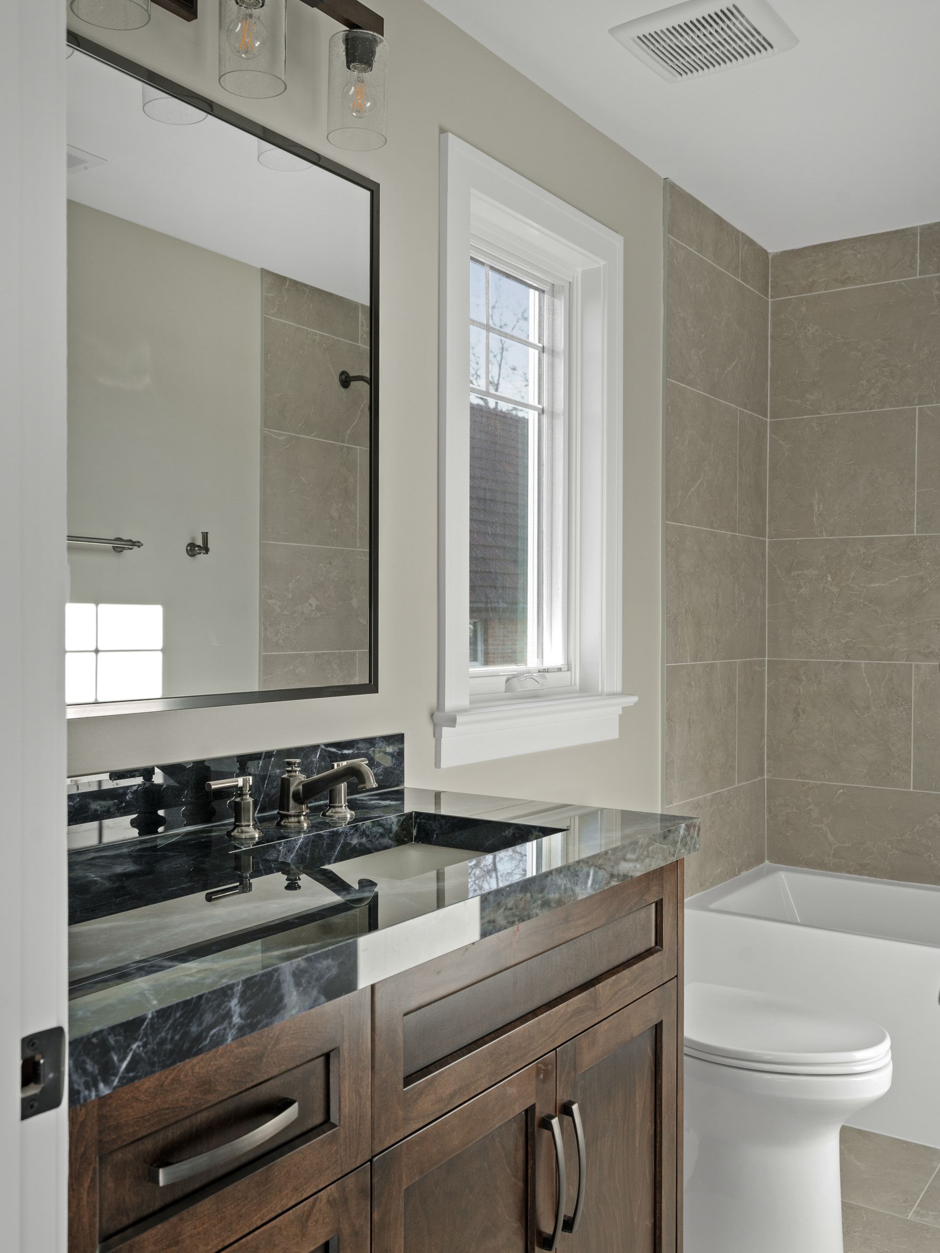 A bathroom with a sink , toilet , tub and mirror.