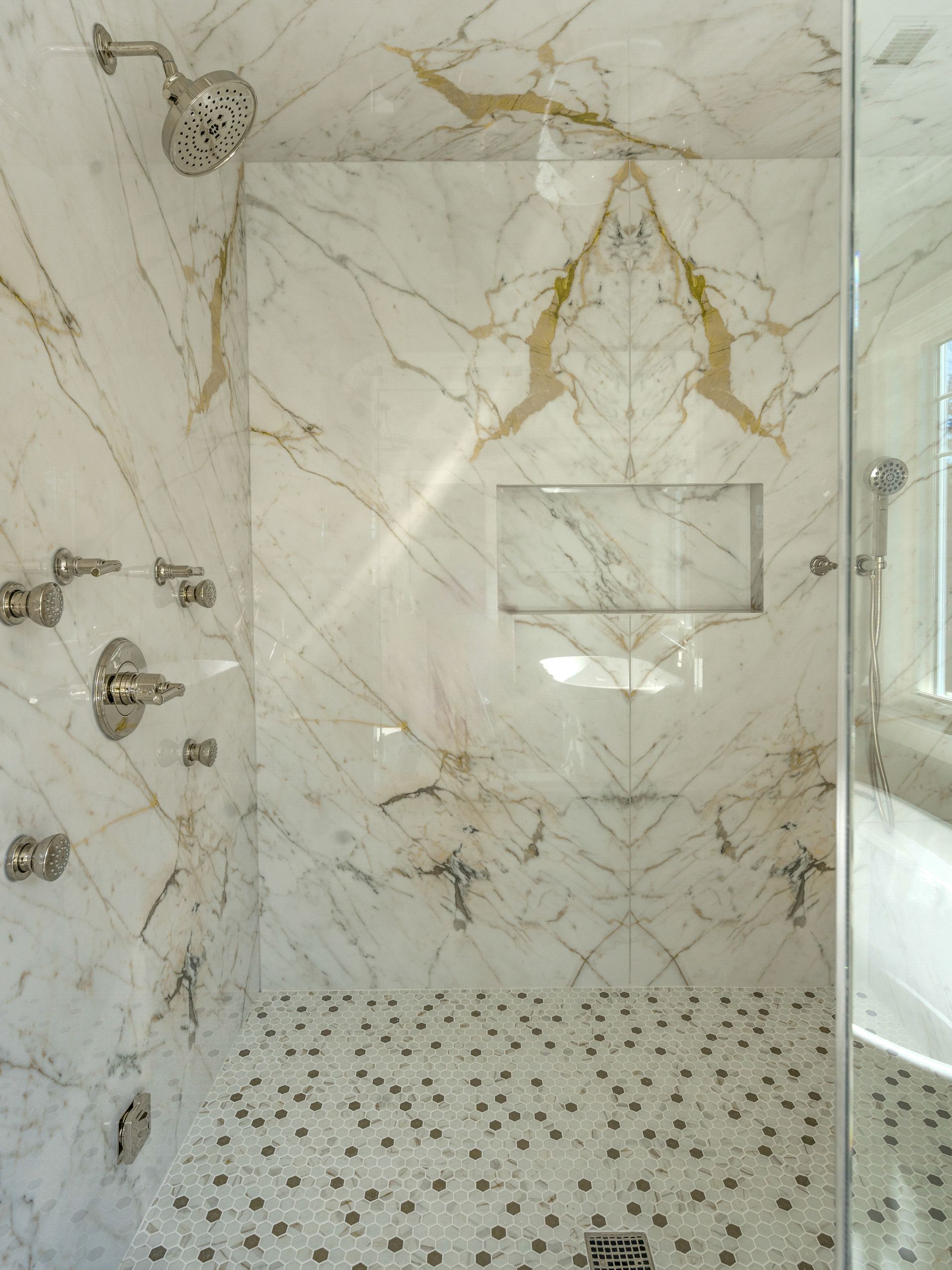 A bathroom with a walk in shower and marble walls.