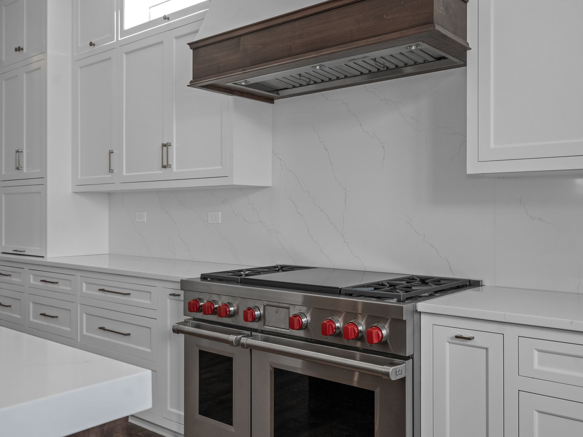 A kitchen with white cabinets and a stove and oven.