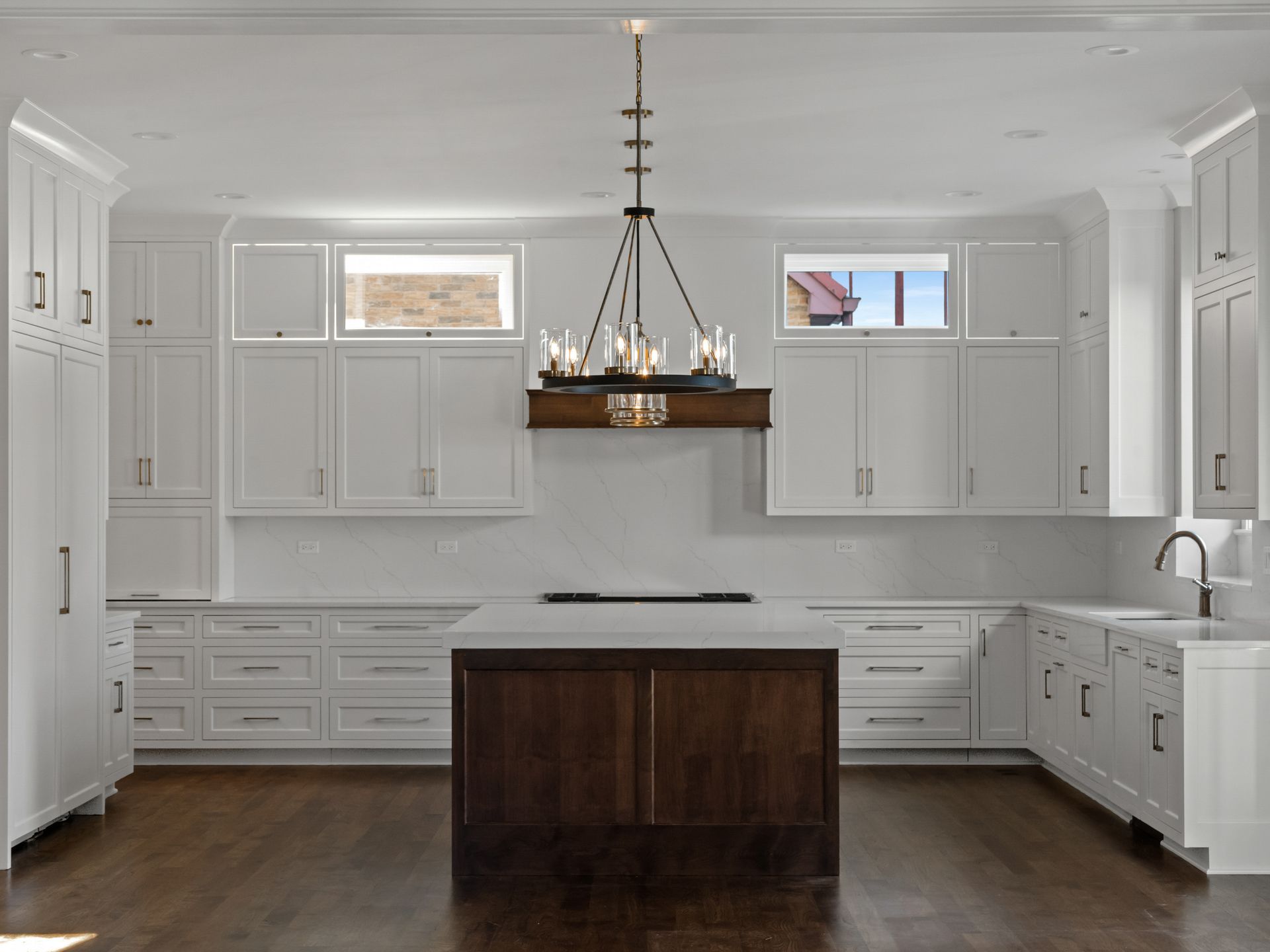 A kitchen with white cabinets and a large island with a chandelier hanging from the ceiling.