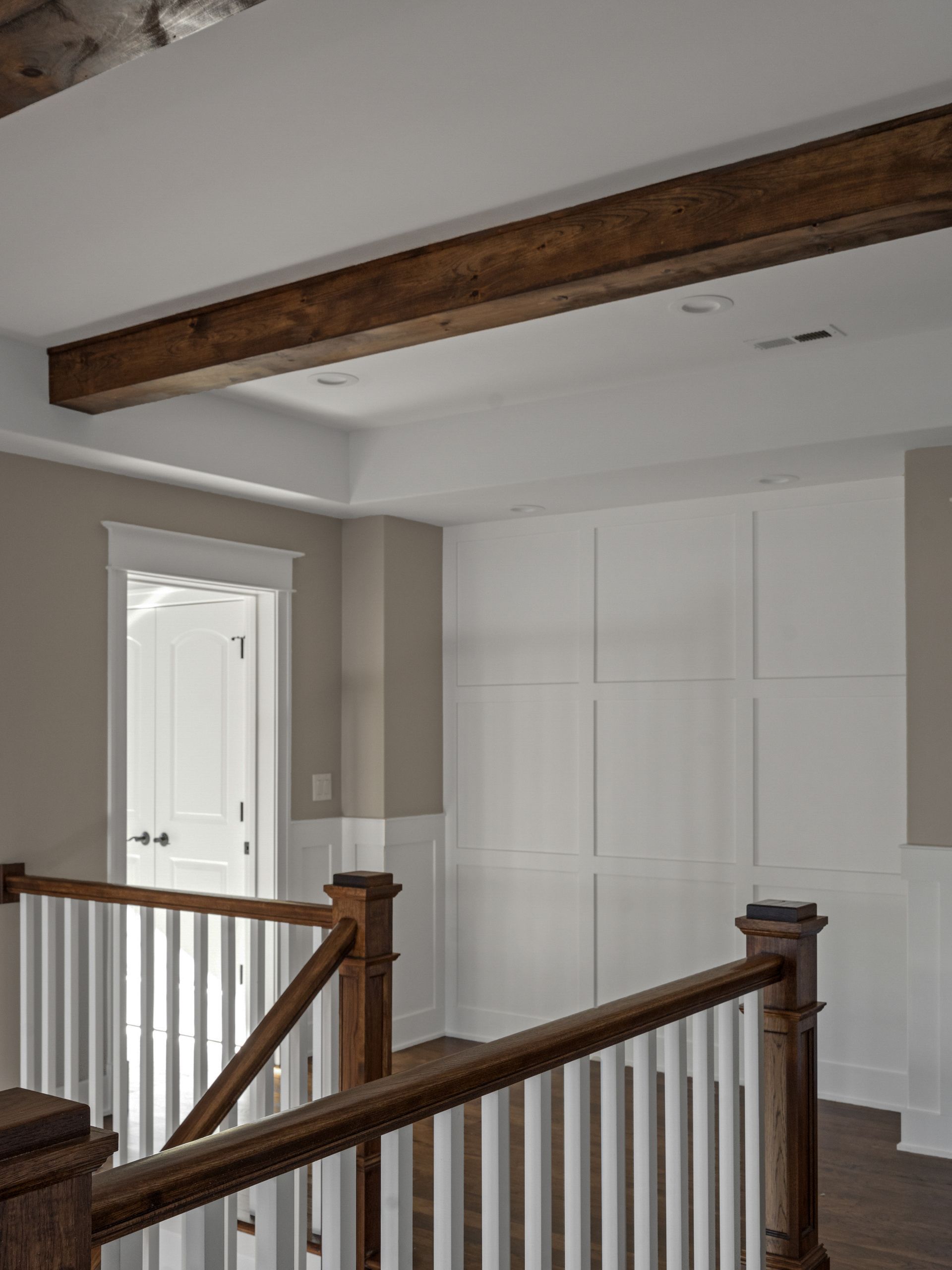 A staircase with a wooden railing and a wooden beam hanging from the ceiling.