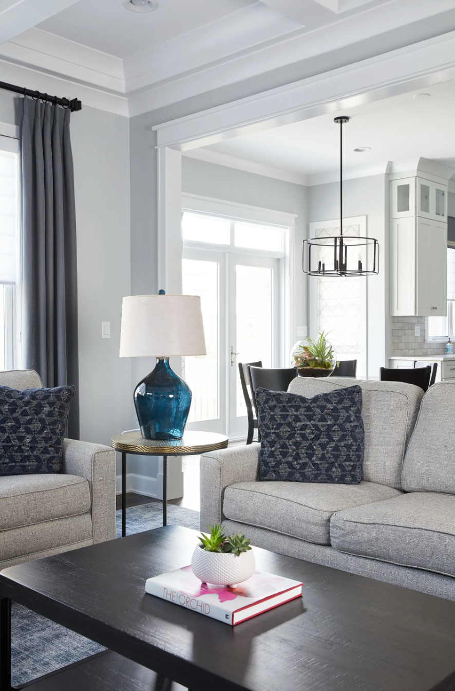 A living room with a couch , chairs , coffee table and lamp.
