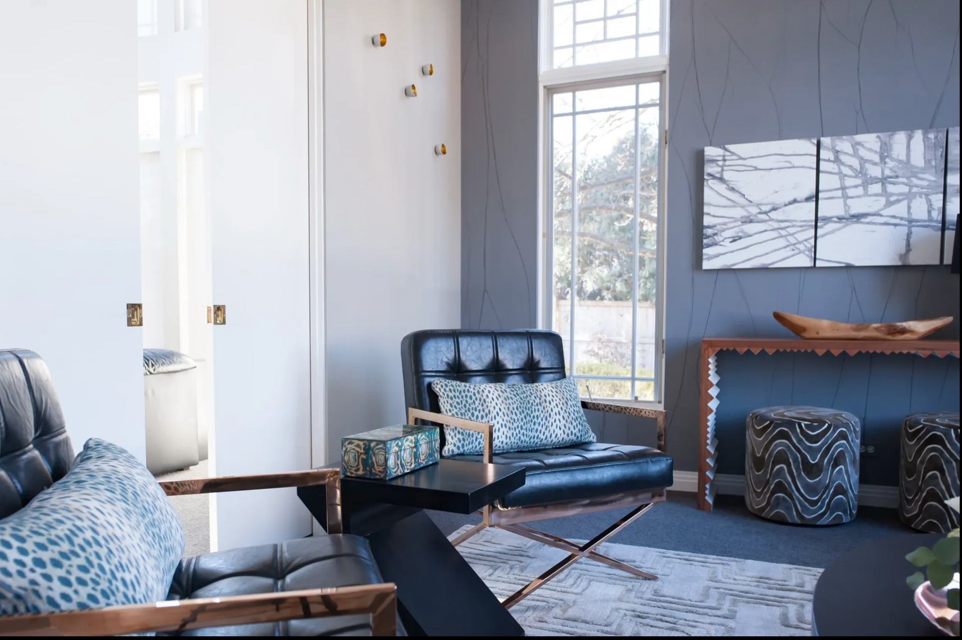 A living room with a couch , chairs , ottomans and a table.