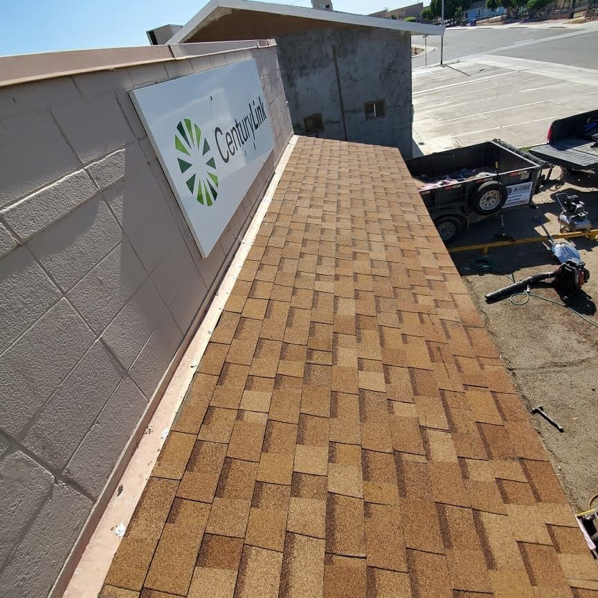 Brown shingled roof next to a beige building with a sign that says 