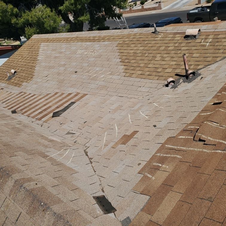 Damaged residential roof with missing and cracked shingles.