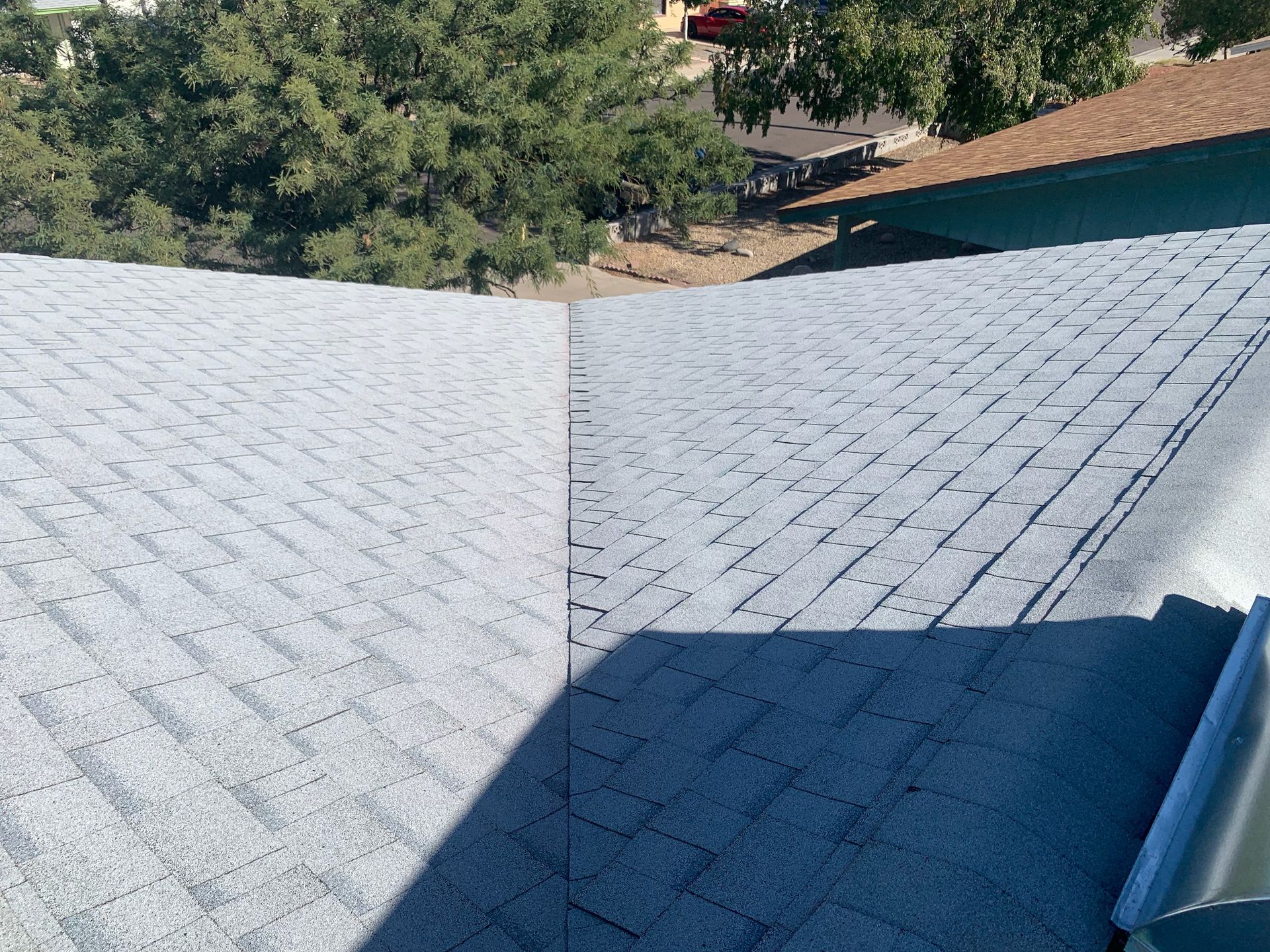 Gray asphalt shingle roof, sunlight casts shadows.