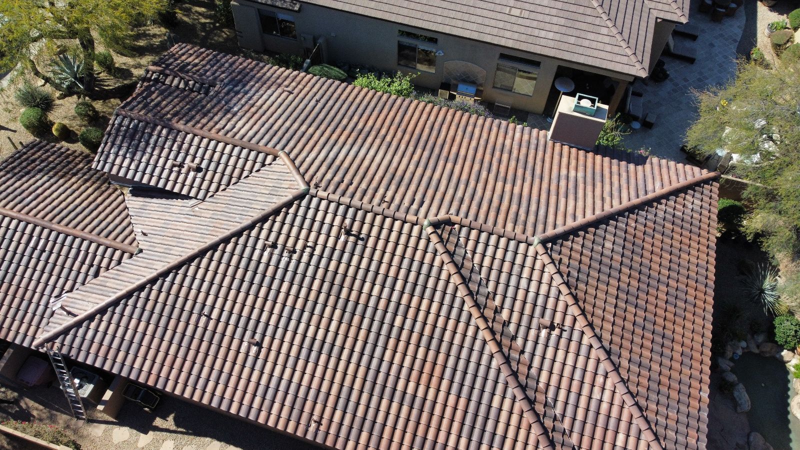 Overhead view of a terracotta tiled roof on a house with multiple sections.