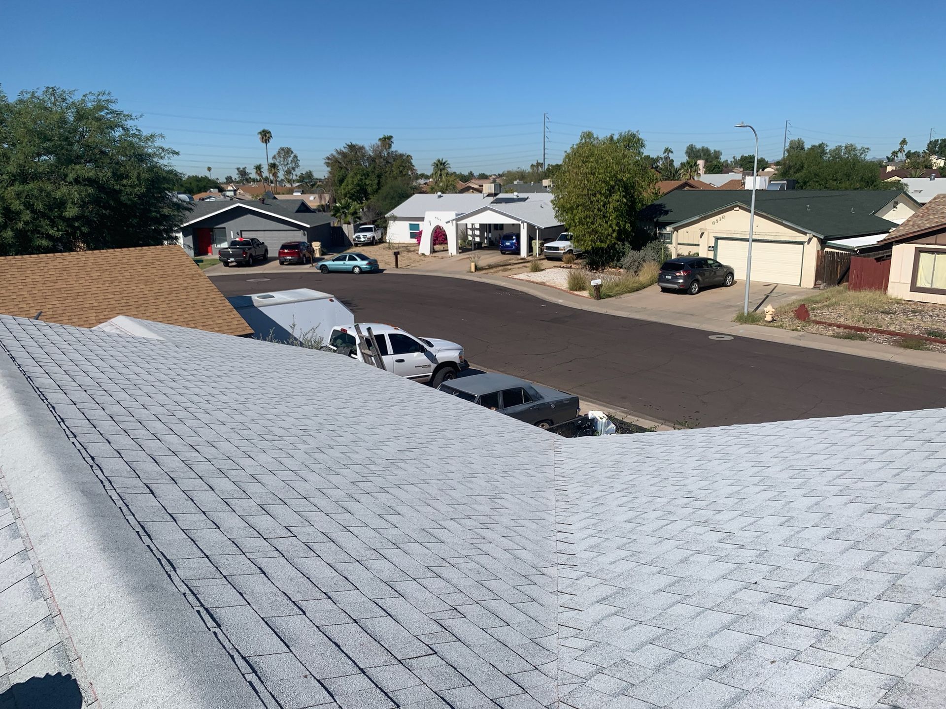 View from a roof of suburban street with cars parked in driveways and on the road.