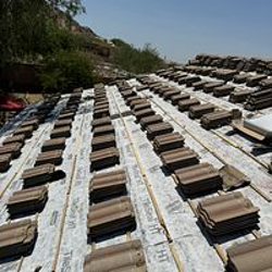 Roof under construction with neatly arranged brown tiles.