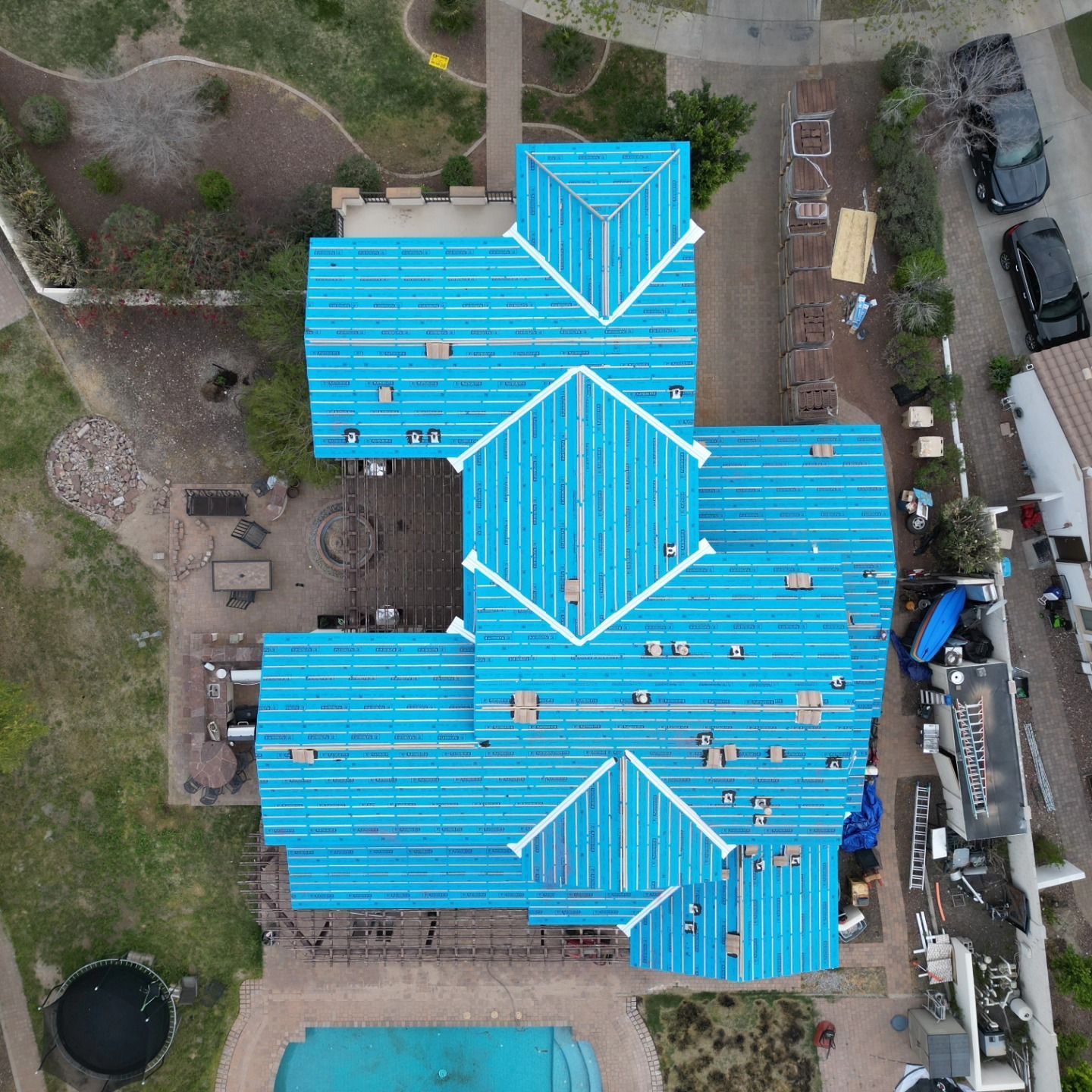 Aerial view of a house with blue tarps covering a partially replaced roof.