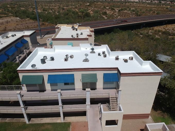 Building exterior with white roof, awnings, and equipment; a highway is visible in the background.