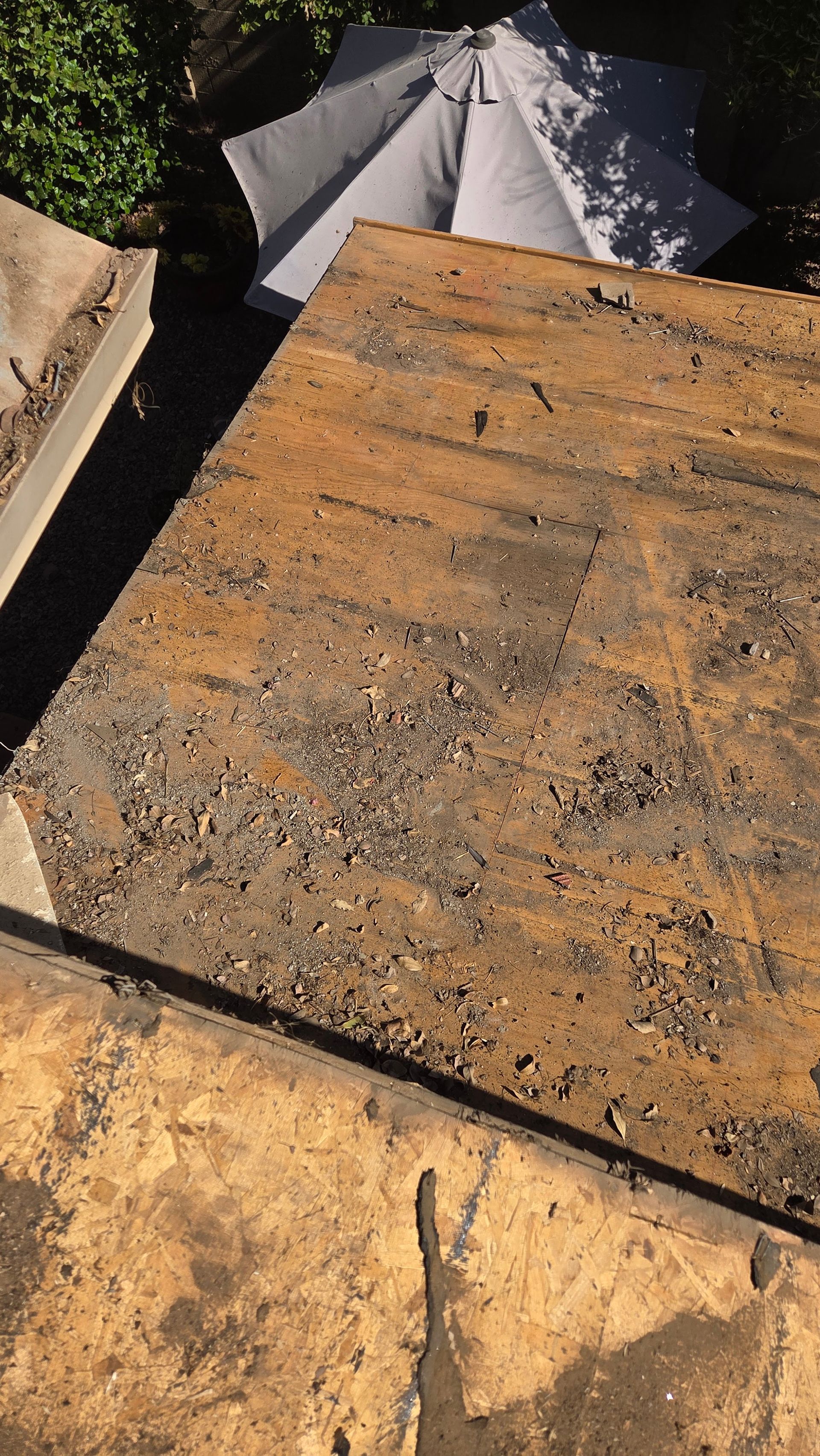 View from above of weathered rectangular concrete slabs, with an open gray umbrella and greenery in the background.