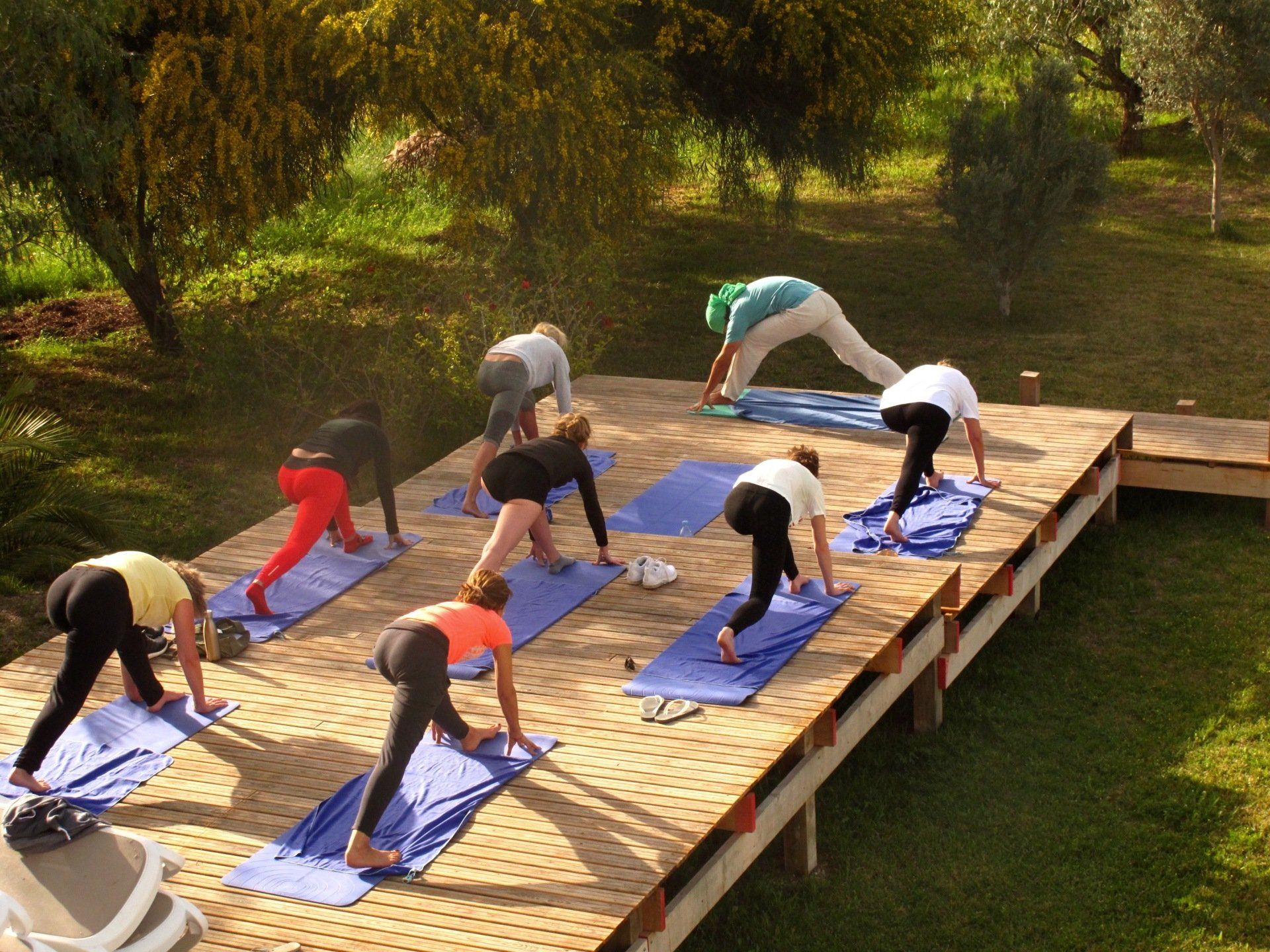 Un groupe de personnes fait du yoga sur une terrasse en bois