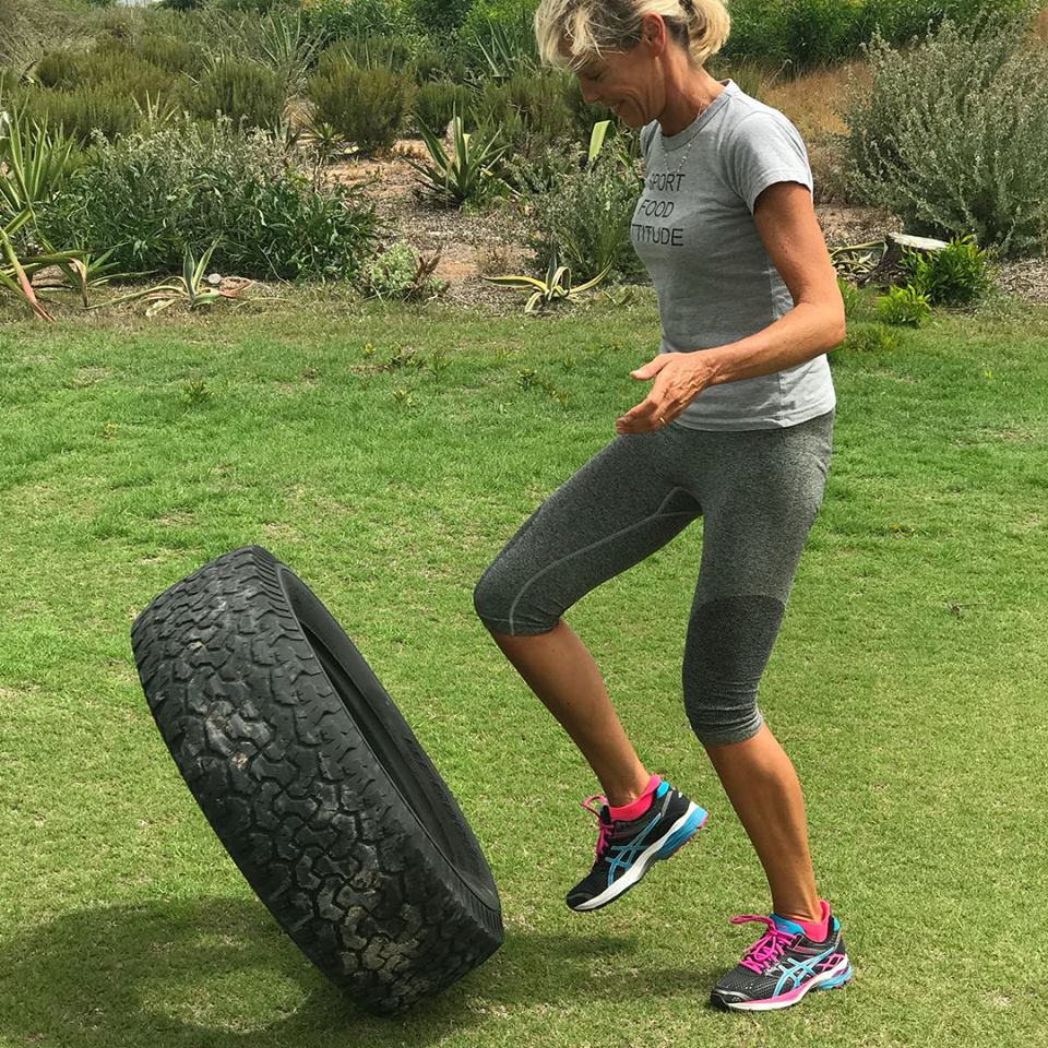 Une femme se tient debout à côté d'un pneu sur l'herbe.