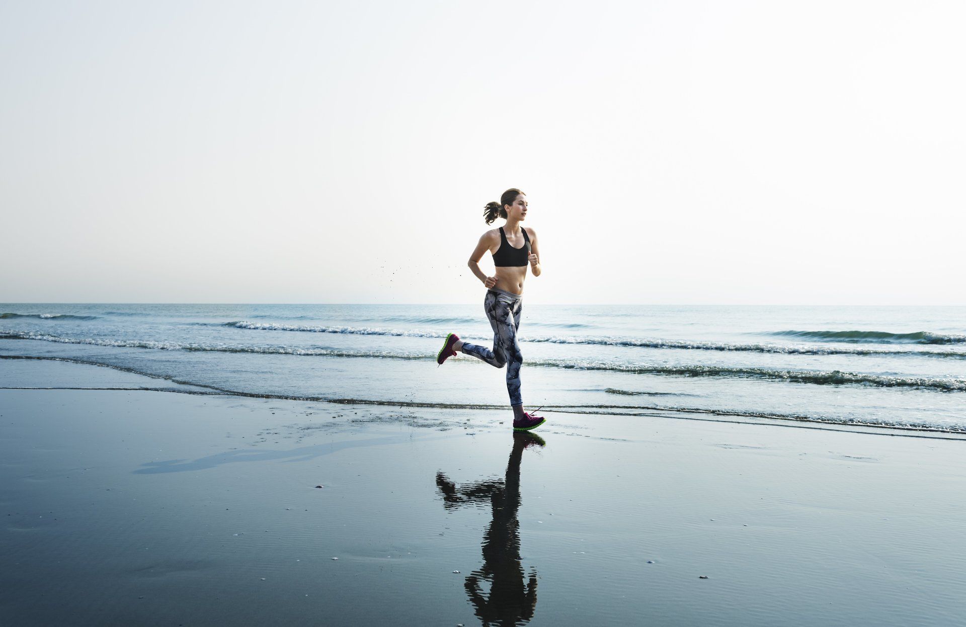 Une femme court sur la plage près de l'océan.