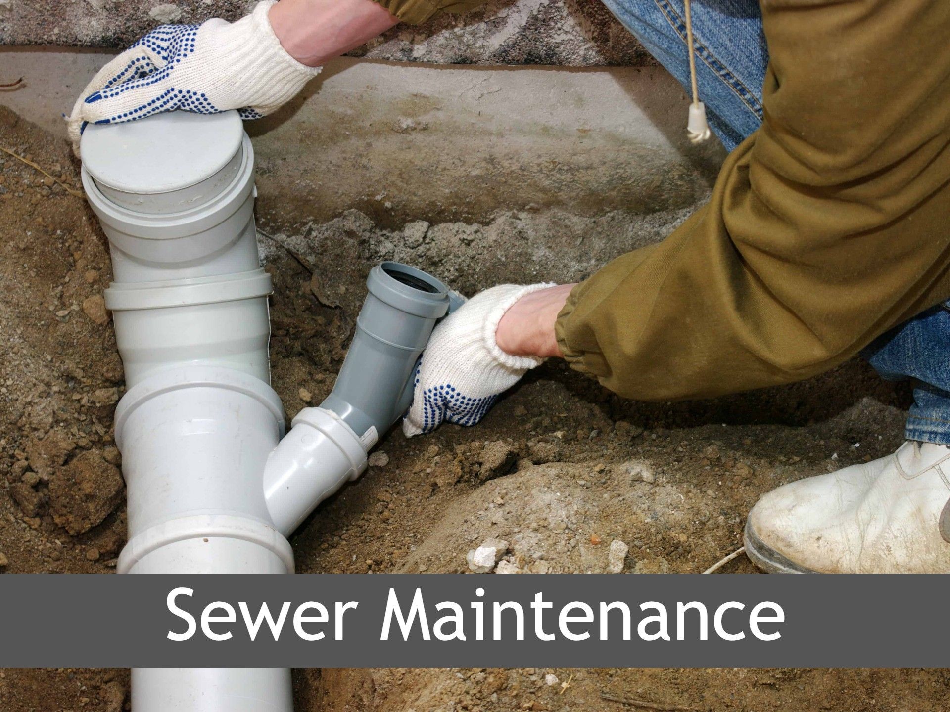 A person is working on a sewer pipe in the dirt.
