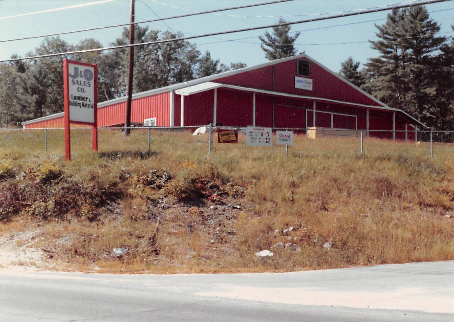 Red building with sign for J&O Sales Co. on a grassy hill.