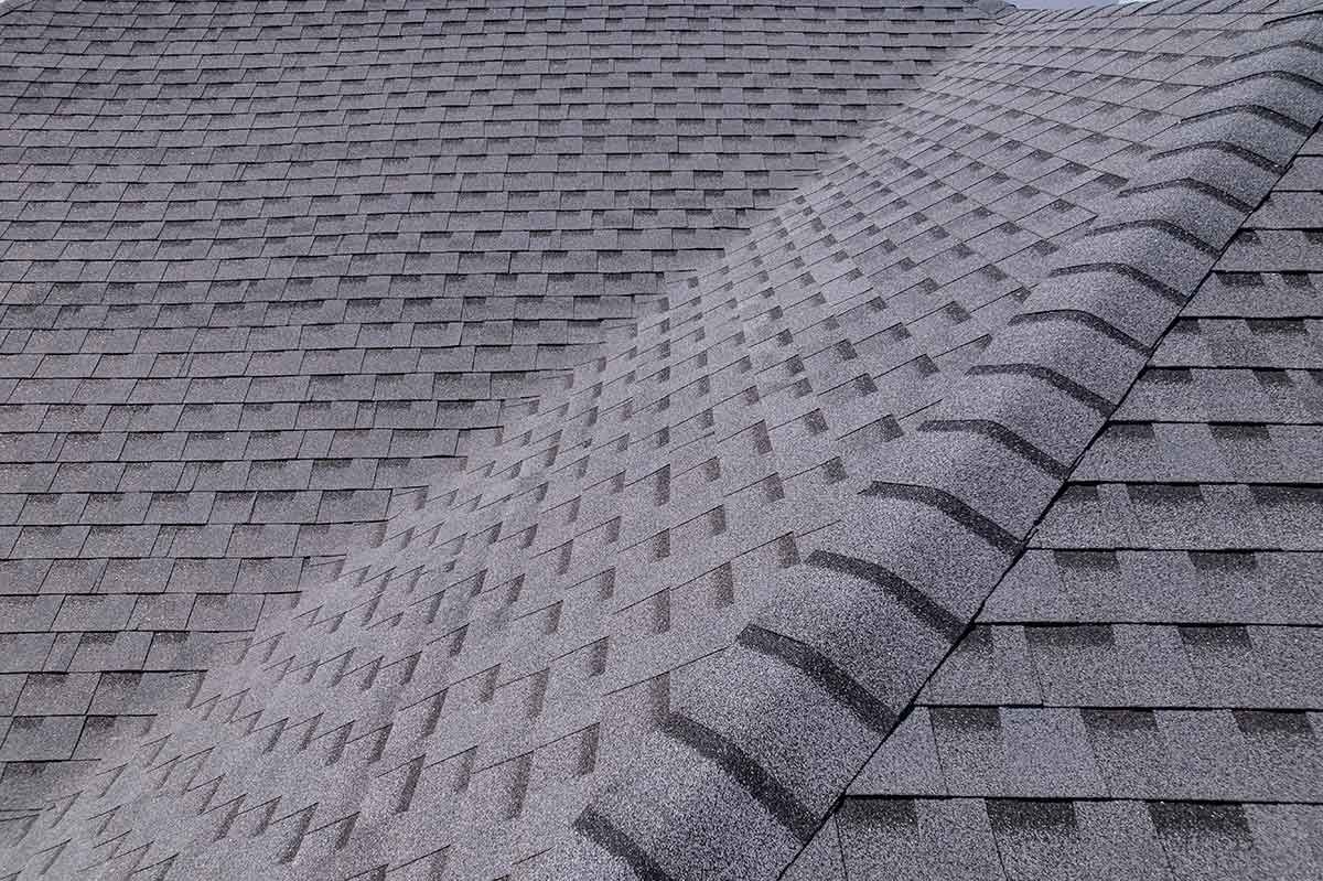 Gray asphalt shingle roof, showing angled hip and ridge detailing on a residential home.