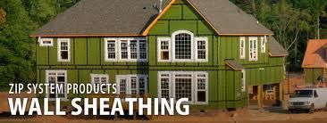 House under construction, showing green wall sheathing. Text reads 