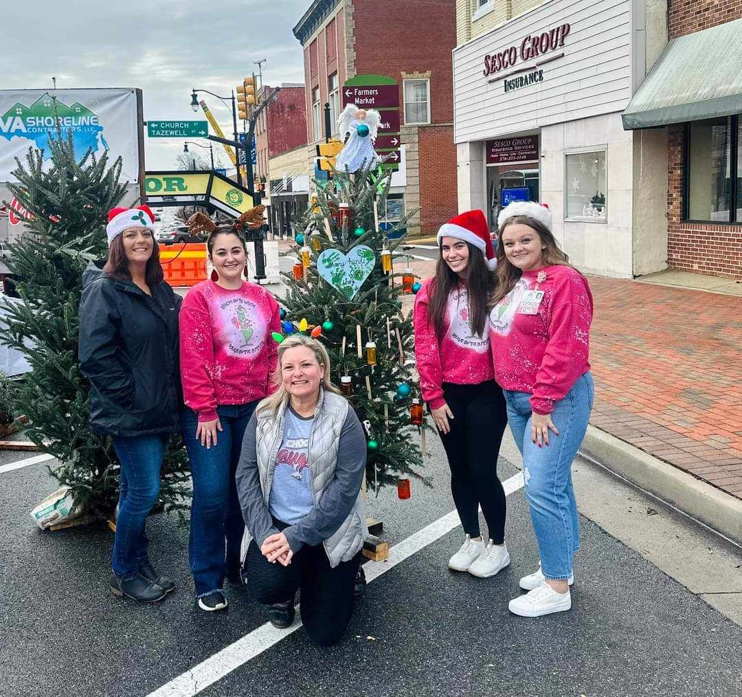 A group of women are posing for a picture in front of a christmas tree.