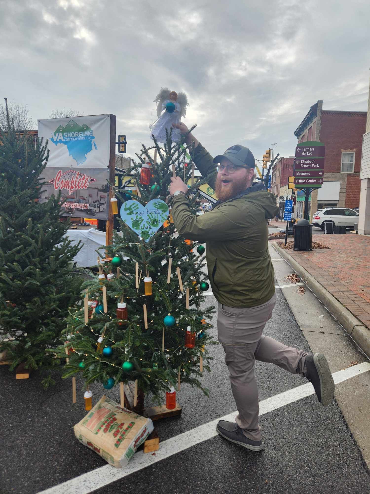 A man is decorating a christmas tree on the side of the road.