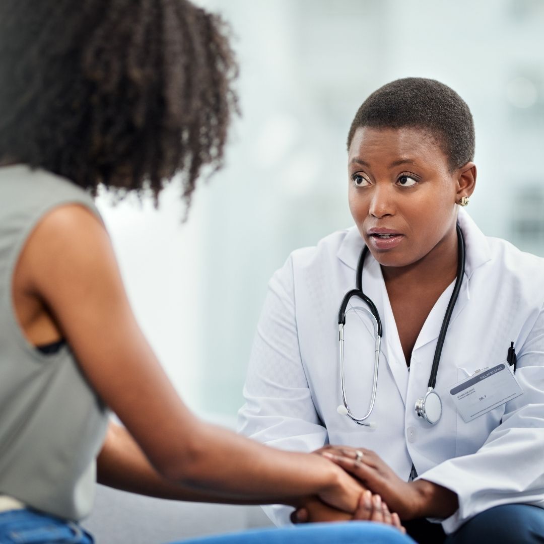 A doctor with a stethoscope around her neck is talking to a patient