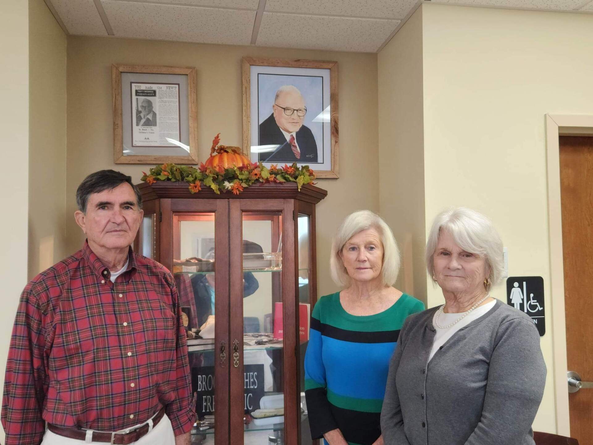A man and two women standing in front of a cabinet