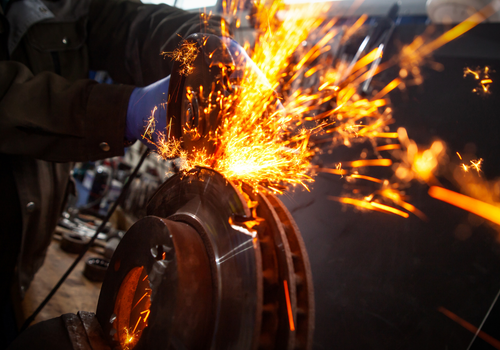 Worker grinding metal with sparks flying in a fabrication shop.
