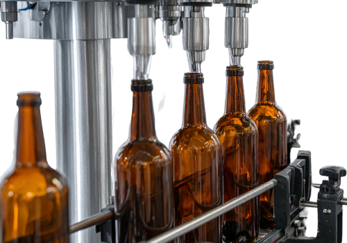 Worker in gloves monitoring a food production line filling metal containers.