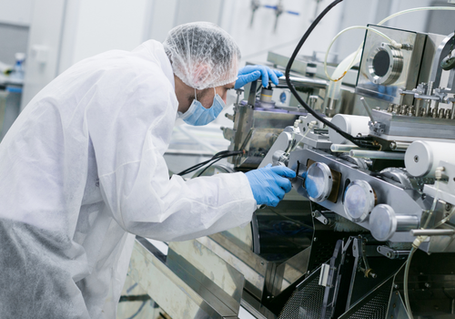 Technician in protective gear operating chemical processing equipment.