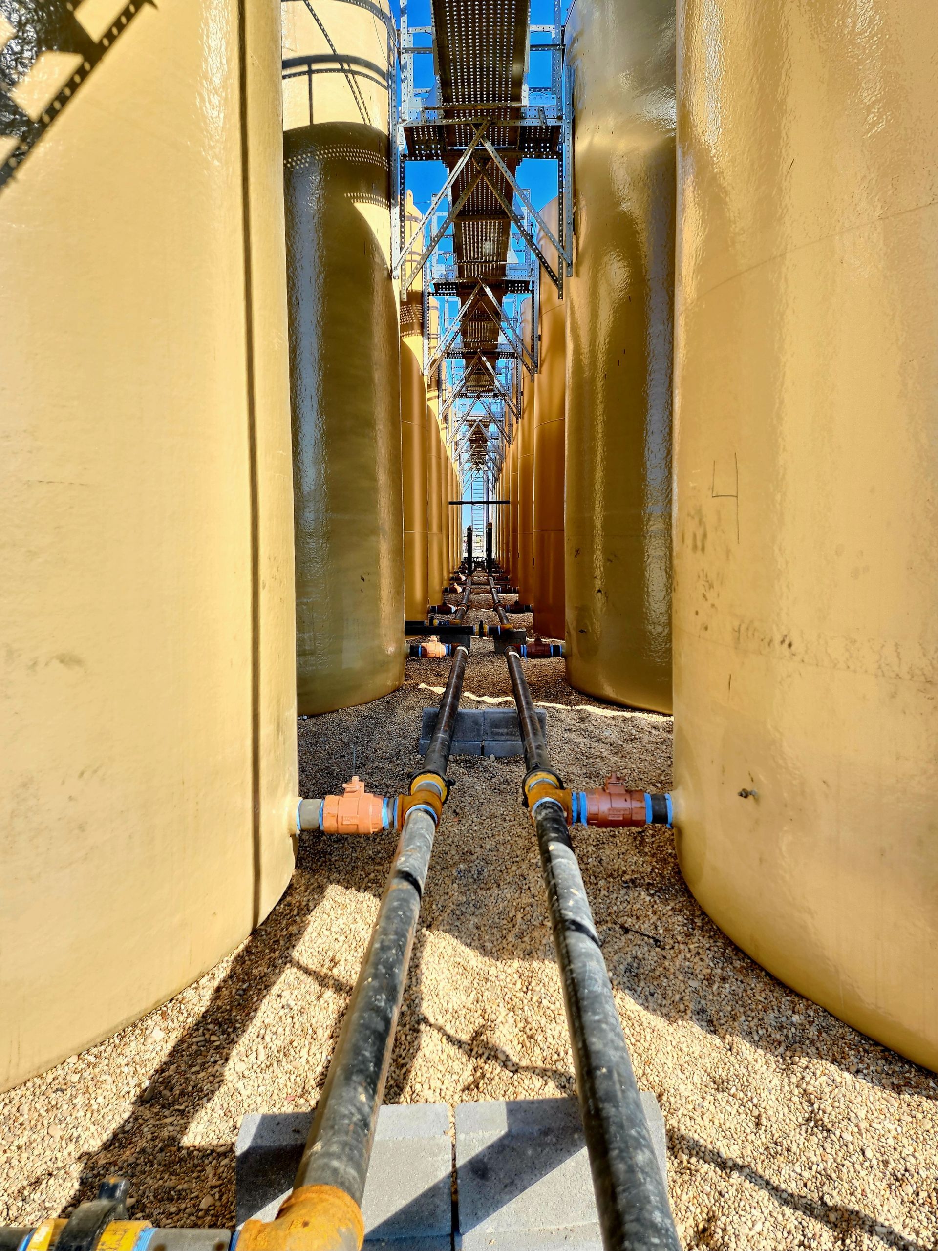 Large Tanks are lined up next to each other in a Factory - Dime Box, TX - Diamond P. Lease & Well Service Inc.