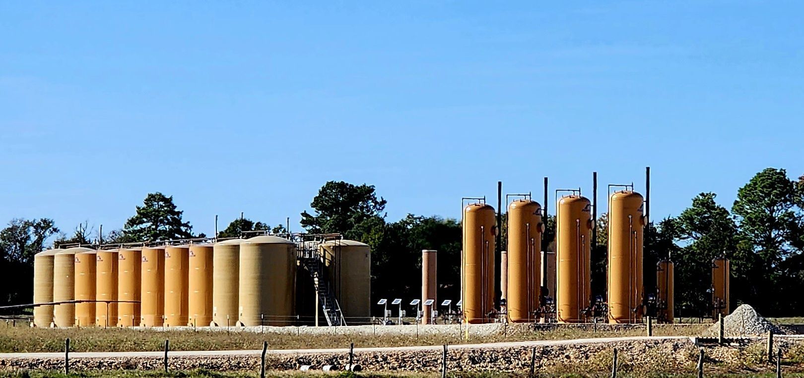 Yellow Tanks are lined up in a Field - Dime Box, TX - Diamond P. Lease & Well Service Inc.
